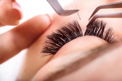 woman with tweezers putting in lash extensions