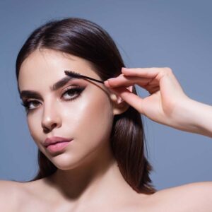 Woman brushing eyebrow with eyelash brush